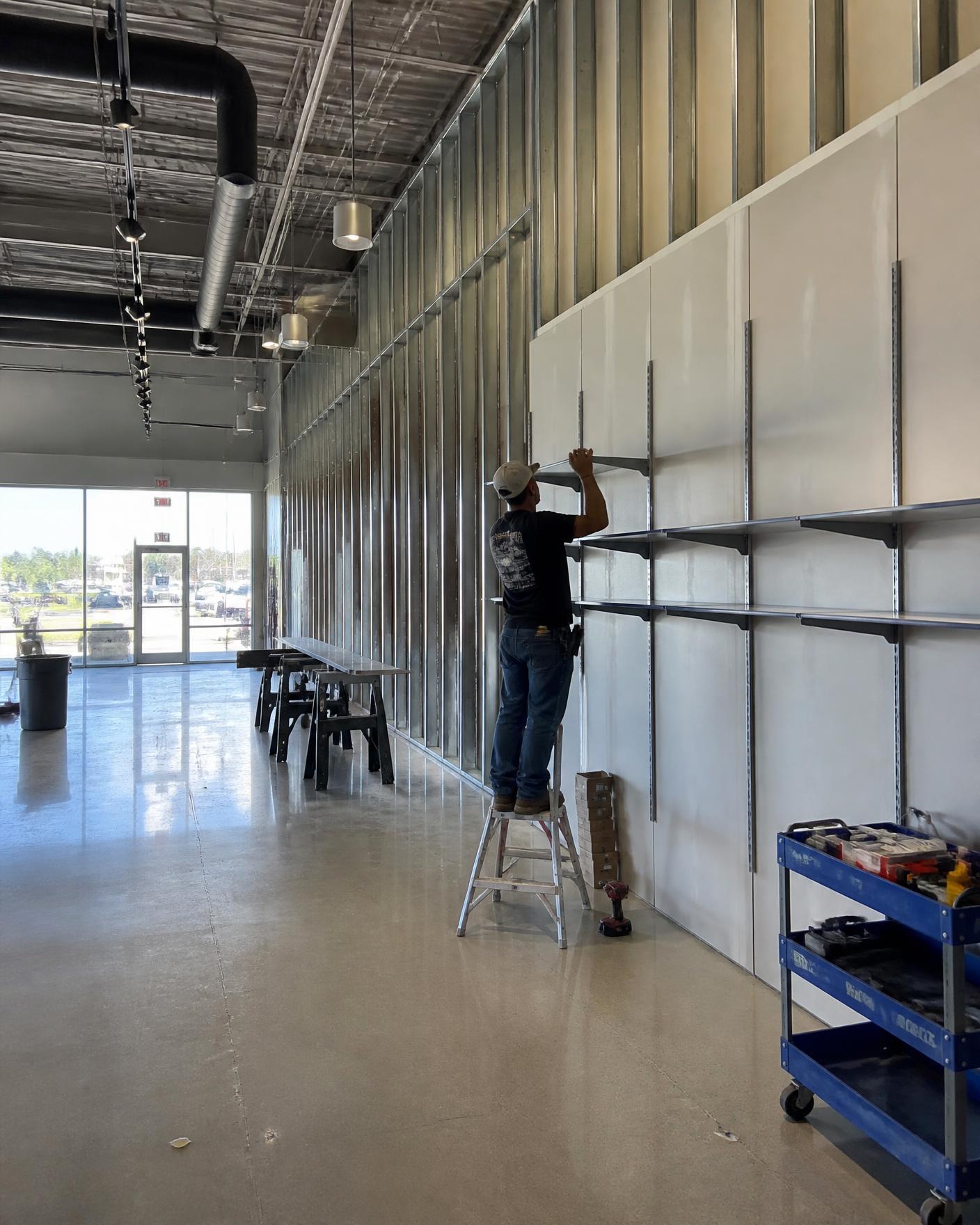 Retail store interior mid-buildout with metal stud framing and new shelving