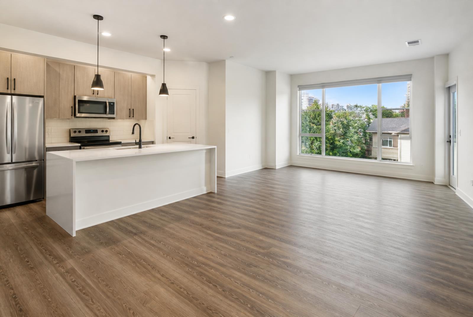 Finished apartment unit interior with open kitchen, island and plank flooring